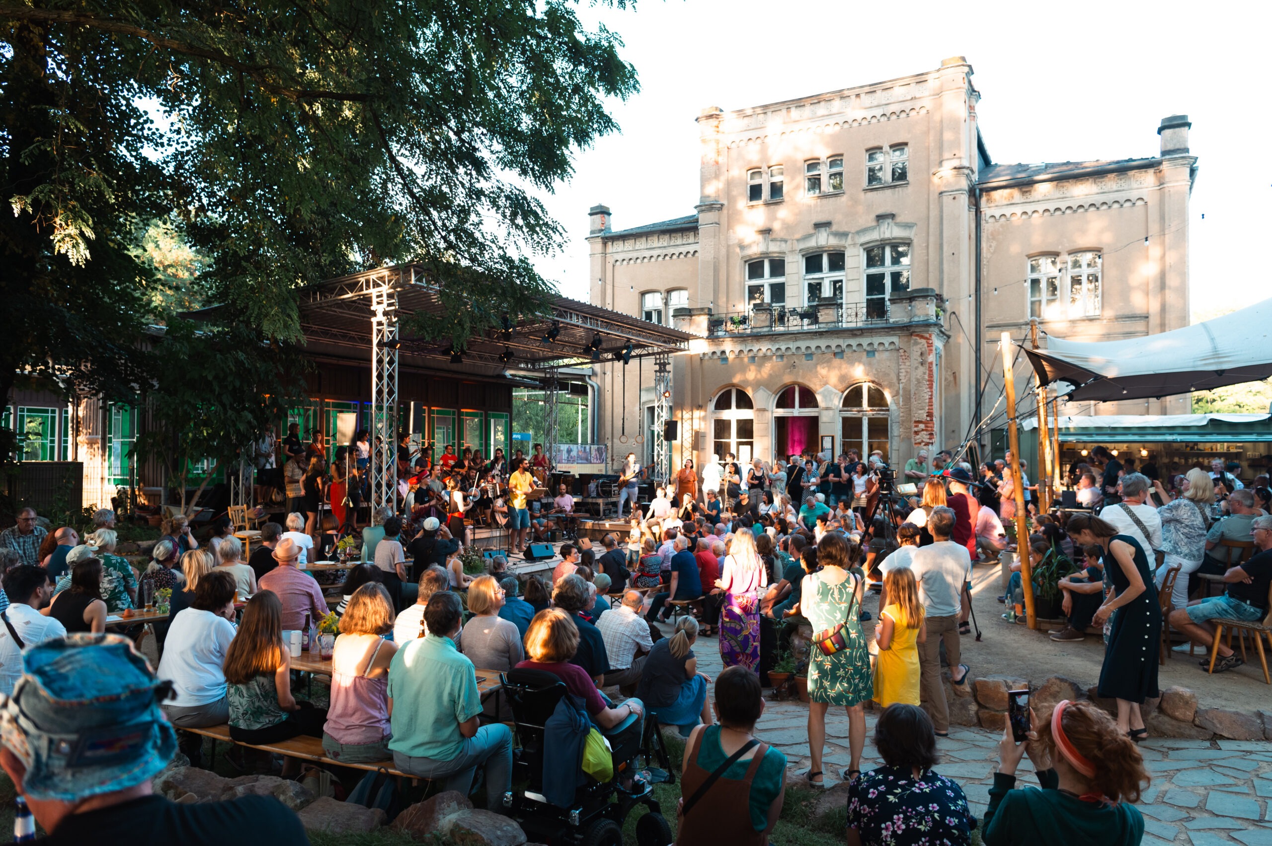 Musiker:innen auf einer Bühne von hinten im Garten des Kulturbahnhof Leisnig