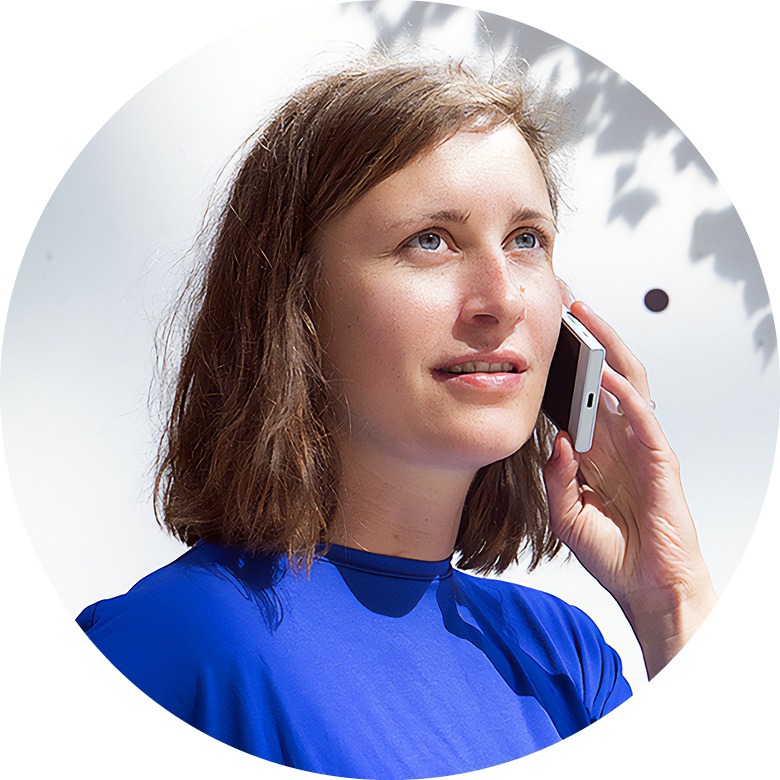 Frau mit hellbraunen schulterlangen Haaren und blauem Pulli telefoniert