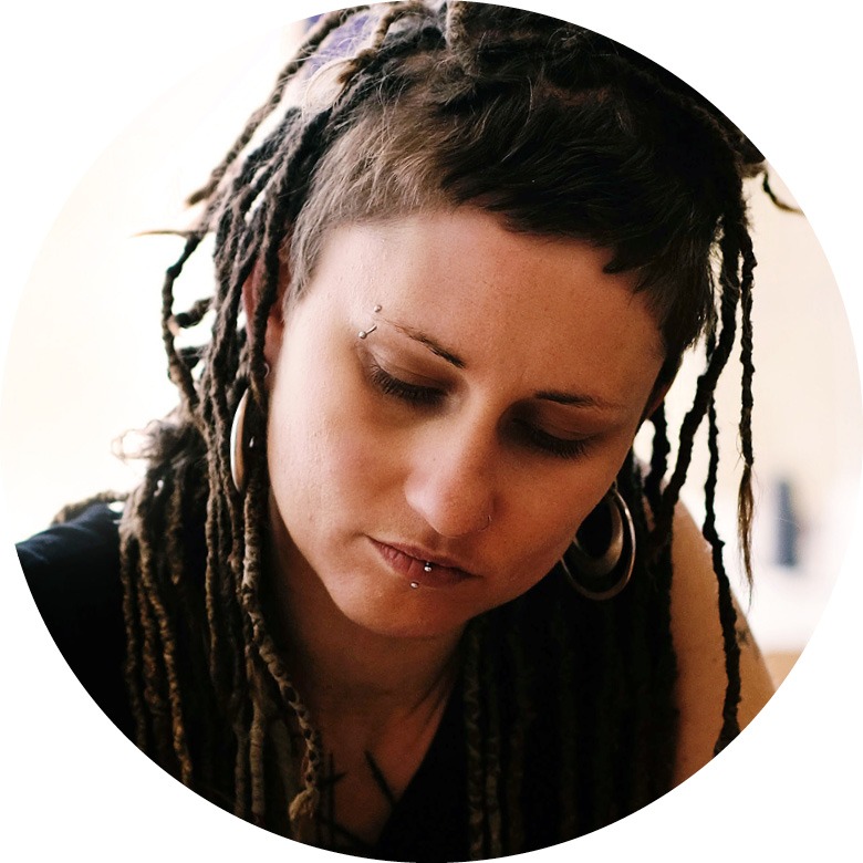Frau mit Dreadlocks im Porträt, sie schaut nach unten.