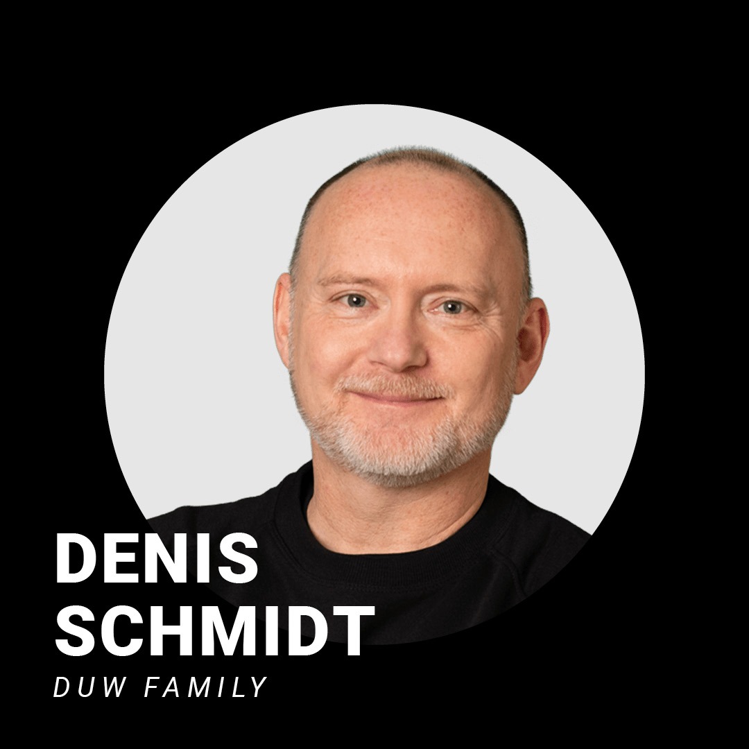 Weißer mittelalter Mann mit Halbglatze und grauem Dreitagebart lächelt freundlich in die Kamera. Schriftzug: Denis Schmidt, DuW family.